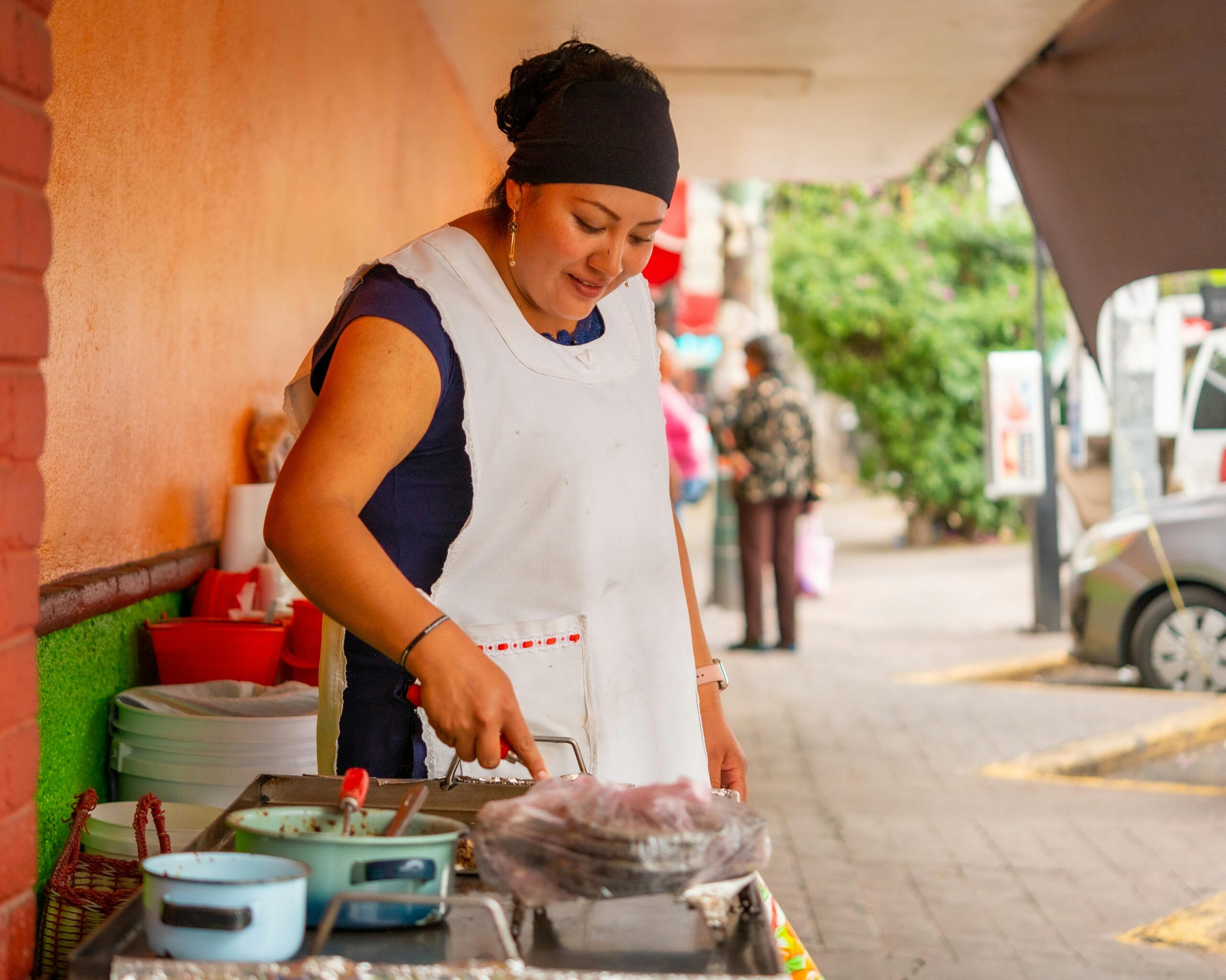 A woman preparing street food at an outdoor market in Ciudad de México. Captured in a vibrant urban setting.