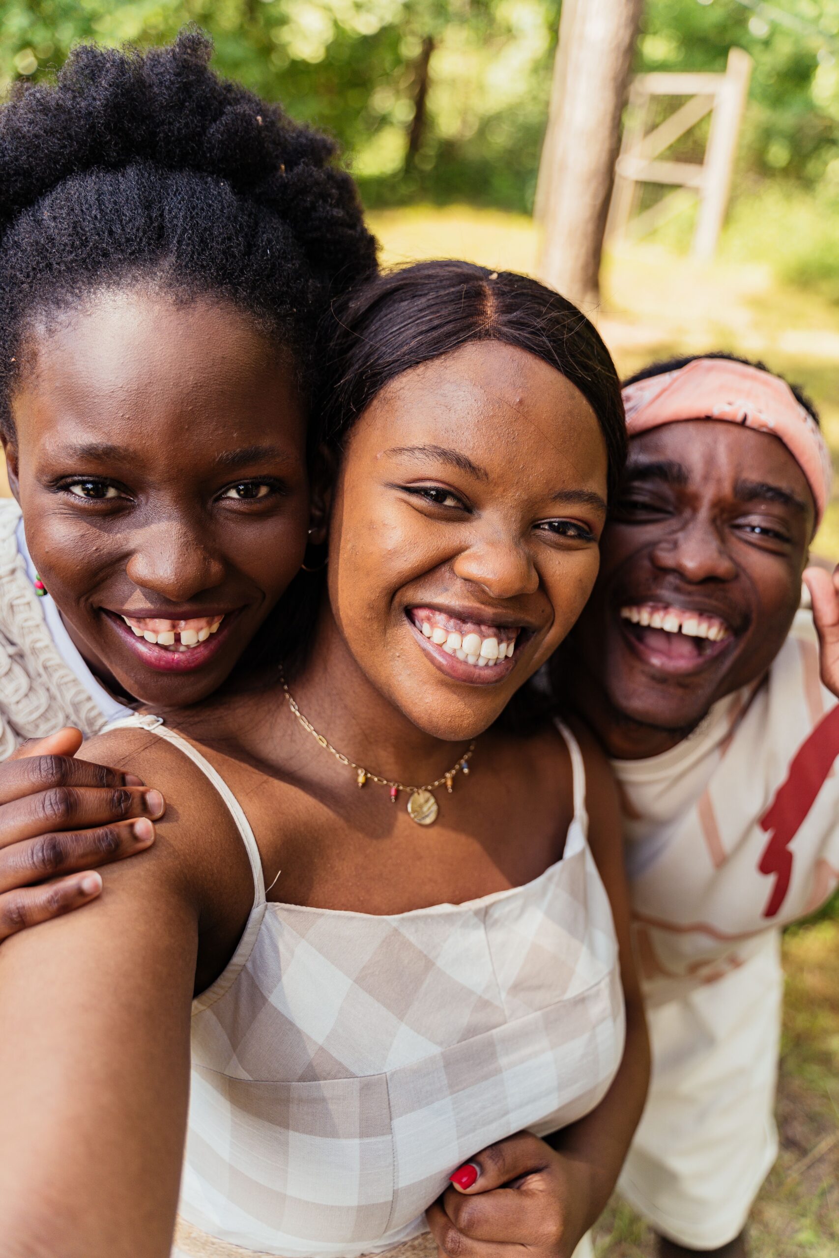 Three friends laughing and taking a selfie outdoors, showcasing happiness and friendship.